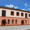 Dwupiętrowy dom w jasnych i ciemnych odcieniach pomarańczy, z czerwonymi cegłami wokół okien i drzwi