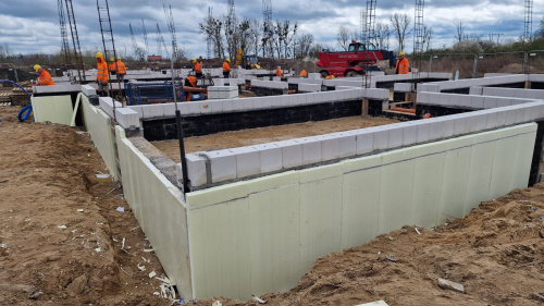 Widok na plac budowy z metalowymi prętami i płytami betonowymi