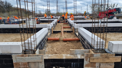 Widok na plac budowy z metalowymi prętami i płytami betonowymi