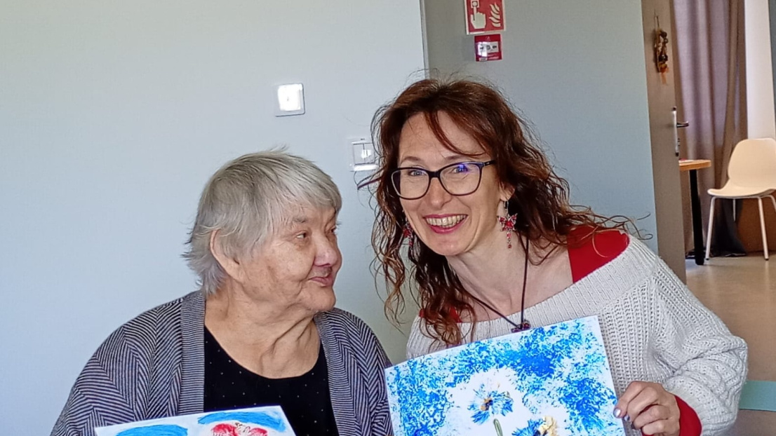 Młoda kobieta i starsza kobieta siedzą przy stole, prezentując swoje wspaniałe dzieła sztuki.