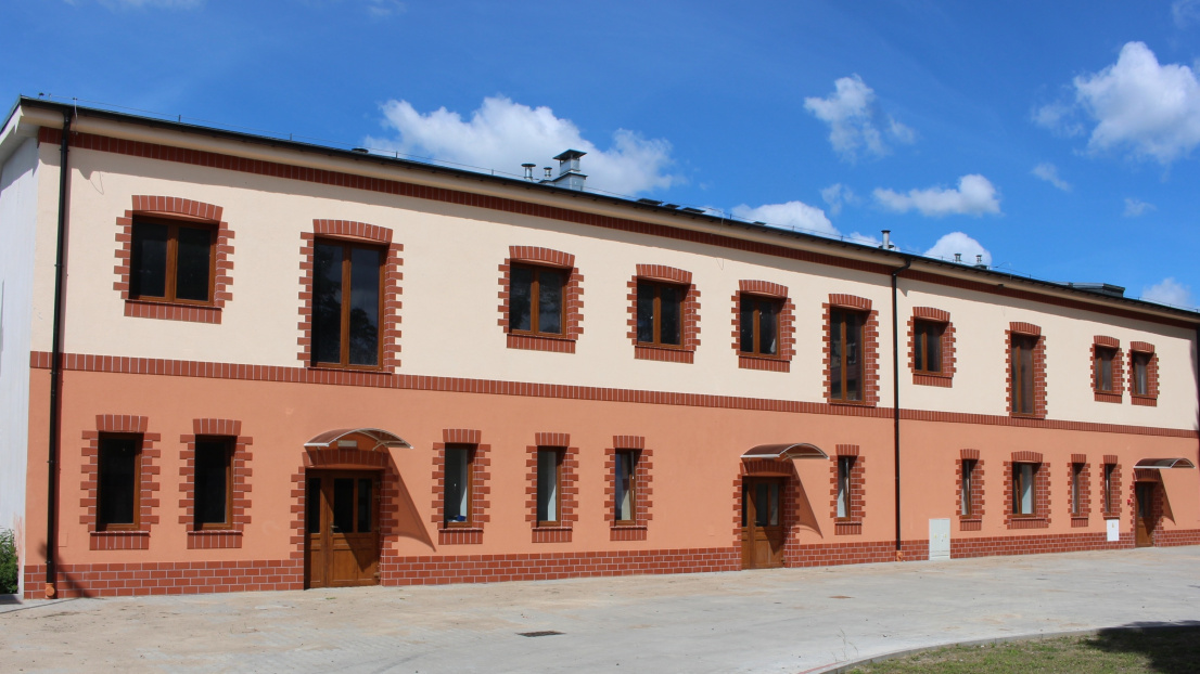 Dwupiętrowy dom w jasnych i ciemnych odcieniach pomarańczy, z czerwonymi cegłami wokół okien i drzwi