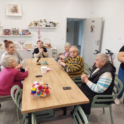 Nowoczesna, jasna sala z dużą przestrzenią, kilka osób siedzi przy stole i rozmawia