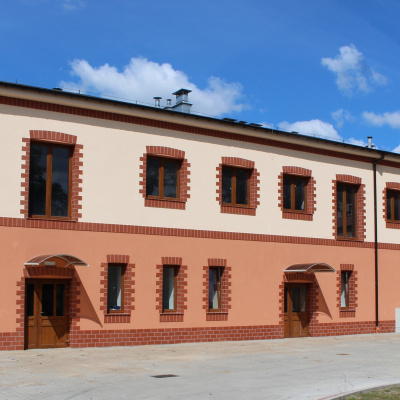Dwupiętrowy dom w jasnych i ciemnych odcieniach pomarańczy, z czerwonymi cegłami wokół okien i drzwi